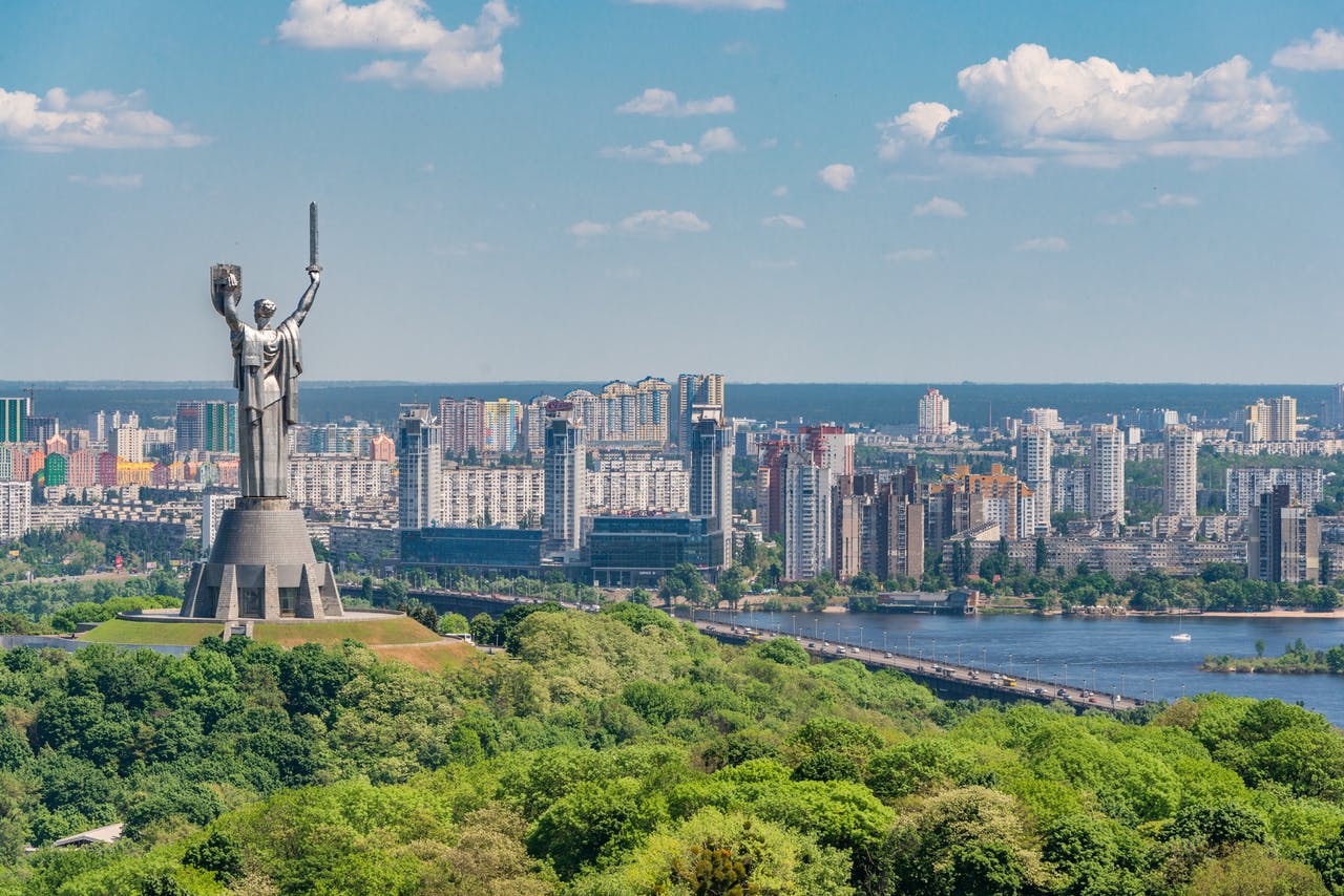 monumento a la patria entre árboles verdes en el terraplén de kiev